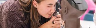 A nursing student uses an otoscope on a patient simulator